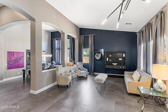 sitting room with arched walkways, an accent wall, visible vents, and baseboards