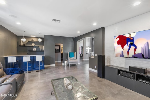 living area featuring visible vents, arched walkways, baseboards, tile patterned floors, and recessed lighting