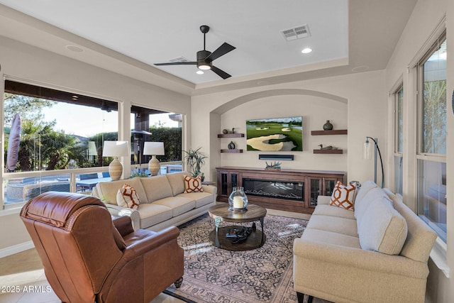 living room with a tray ceiling and ceiling fan