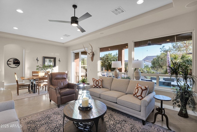 tiled living room featuring ceiling fan and a tray ceiling