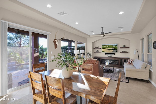 tiled dining space featuring ceiling fan and a raised ceiling