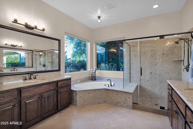 bathroom featuring plus walk in shower, vanity, a wealth of natural light, and tile patterned flooring