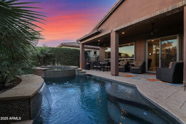 pool at dusk featuring ceiling fan, an outdoor hangout area, an in ground hot tub, and a patio