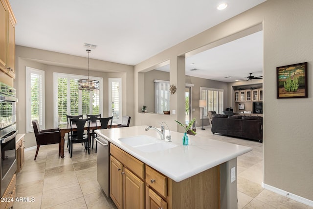 kitchen featuring a kitchen island with sink, a sink, open floor plan, light countertops, and pendant lighting