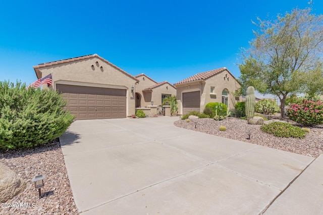 mediterranean / spanish home with a garage, driveway, a tiled roof, and stucco siding