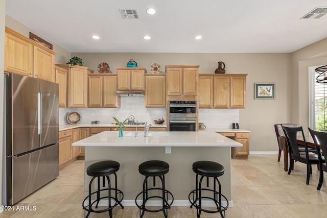 kitchen featuring visible vents, a center island with sink, appliances with stainless steel finishes, and light countertops