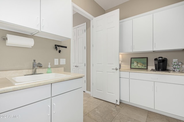 interior space with light tile patterned floors, light countertops, a sink, and white cabinetry