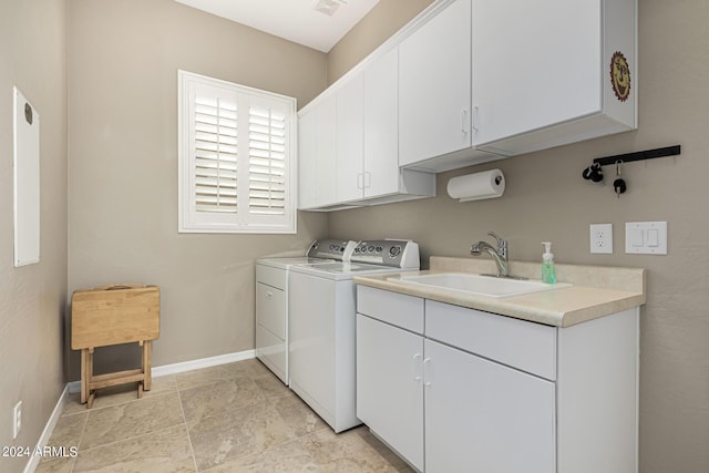 washroom featuring washing machine and clothes dryer, cabinet space, visible vents, a sink, and baseboards