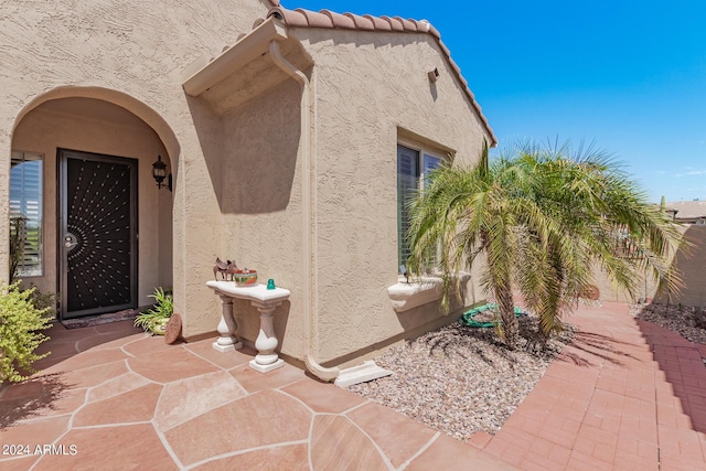 view of exterior entry featuring a tile roof and stucco siding