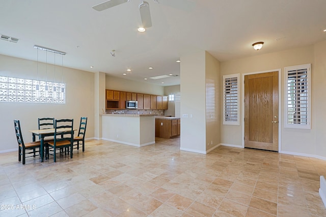 kitchen with hanging light fixtures, backsplash, ceiling fan, and kitchen peninsula