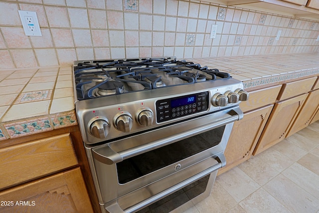 details with tasteful backsplash, tile countertops, and gas stove