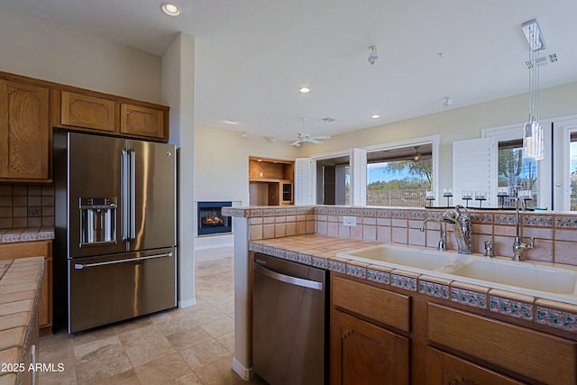 kitchen featuring sink, stainless steel appliances, tasteful backsplash, tile counters, and decorative light fixtures