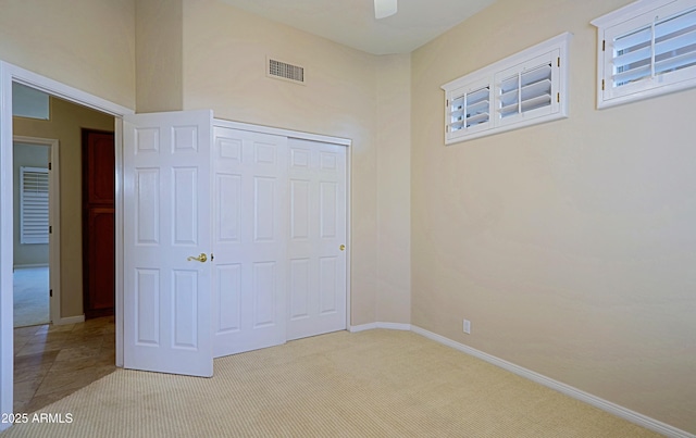 unfurnished bedroom featuring light carpet, ceiling fan, and a closet