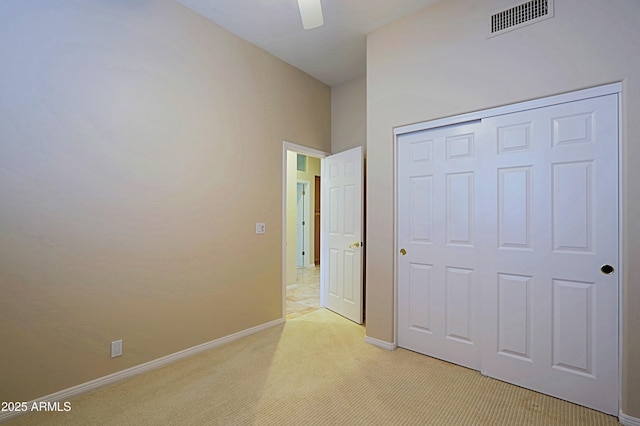 unfurnished bedroom with light colored carpet, ceiling fan, and a closet