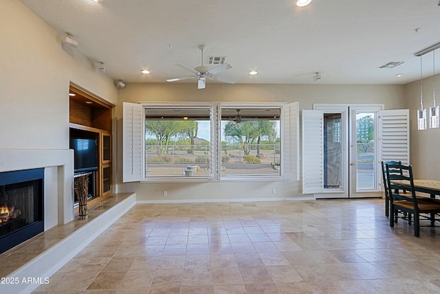 tiled living room featuring ceiling fan, plenty of natural light, a premium fireplace, and built in features