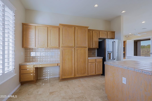 kitchen with built in desk, high quality fridge, tile counters, and decorative backsplash