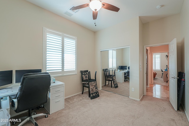 office space with light colored carpet, ceiling fan, and baseboards