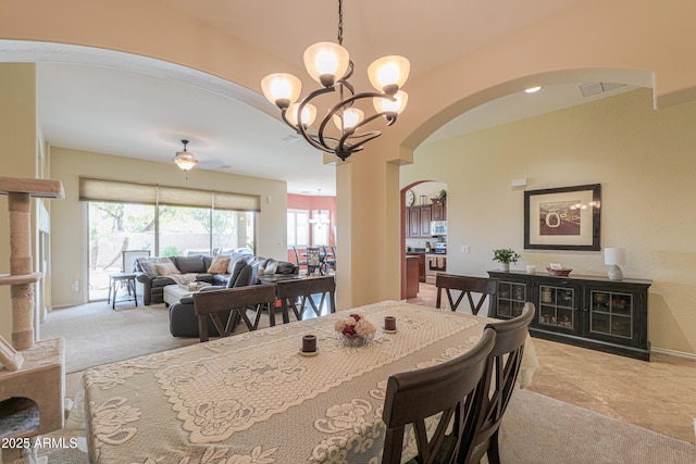 dining space featuring arched walkways, a notable chandelier, visible vents, and carpet floors
