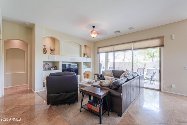 living room featuring built in shelves, visible vents, baseboards, and a healthy amount of sunlight
