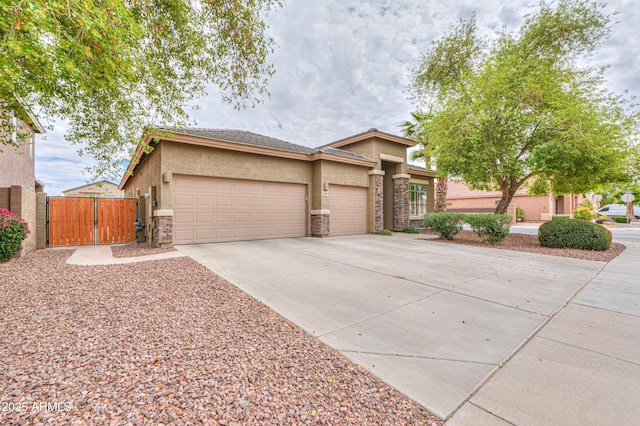 view of front of property featuring stucco siding, driveway, stone siding, a garage, and a gate