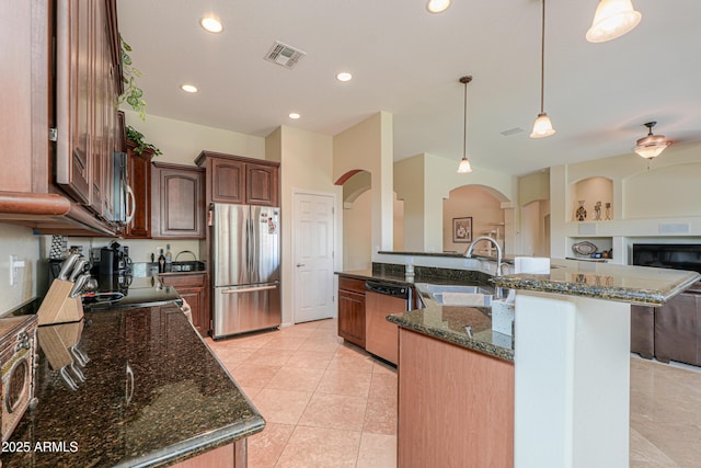 kitchen with visible vents, arched walkways, a sink, open floor plan, and appliances with stainless steel finishes