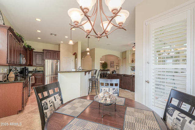 dining space featuring light tile patterned floors, visible vents, arched walkways, a chandelier, and recessed lighting