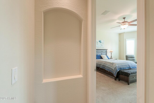 interior space featuring a textured wall, visible vents, and ceiling fan