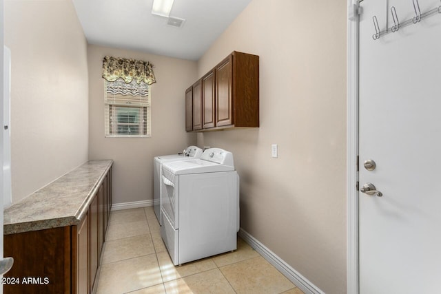 clothes washing area featuring cabinets, washer and dryer, and light tile patterned flooring