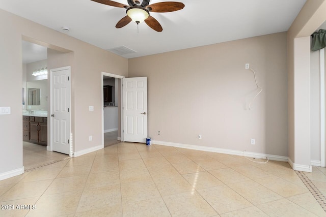 unfurnished bedroom featuring light tile patterned floors, connected bathroom, and ceiling fan