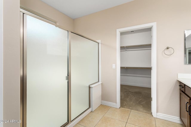 bathroom featuring a shower with door, vanity, and tile patterned flooring