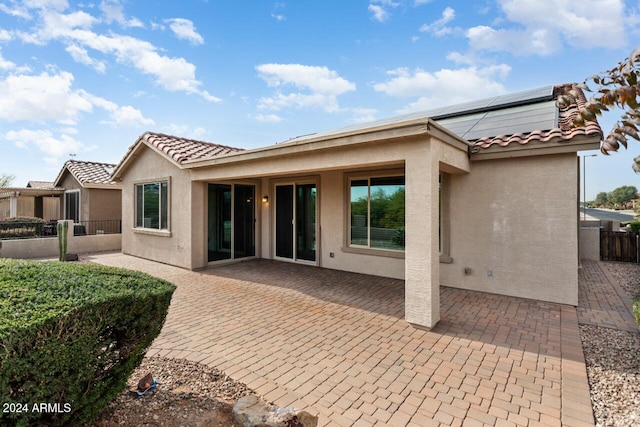 back of property featuring solar panels and a patio area