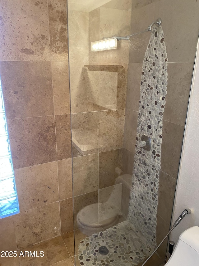 bathroom featuring toilet and a tile shower