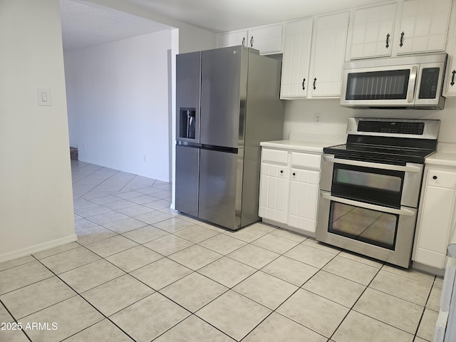 kitchen with stainless steel appliances, light tile patterned floors, and white cabinets