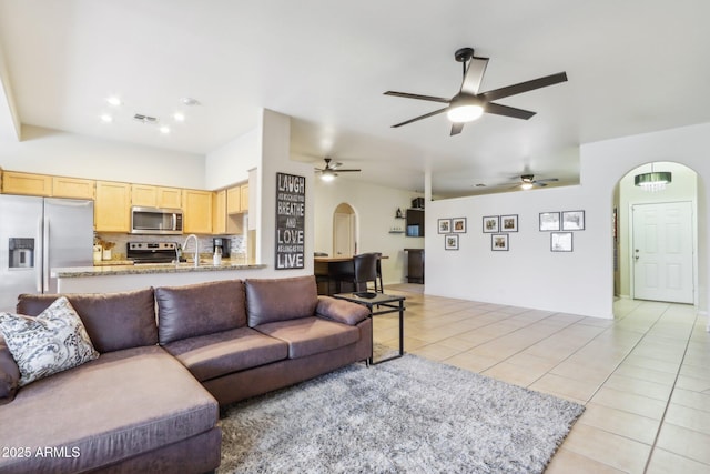 living room featuring arched walkways, light tile patterned flooring, a ceiling fan, and recessed lighting