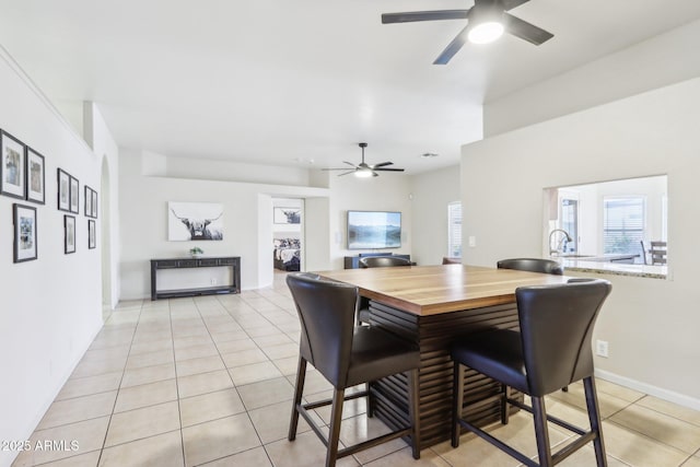 dining space featuring a ceiling fan, light tile patterned floors, and baseboards
