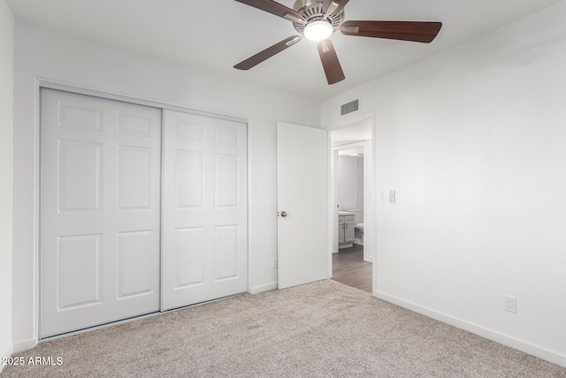 unfurnished bedroom featuring ceiling fan, a closet, and light carpet