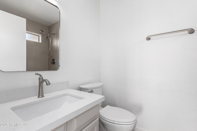 bathroom featuring vanity, a tile shower, and toilet