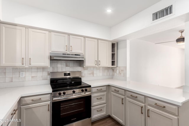 kitchen featuring dark hardwood / wood-style flooring, stainless steel range with electric cooktop, backsplash, and kitchen peninsula