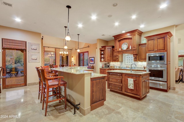 kitchen featuring appliances with stainless steel finishes, a breakfast bar, a spacious island, an inviting chandelier, and hanging light fixtures