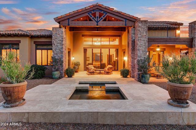 back house at dusk featuring outdoor lounge area, a patio, and an in ground hot tub