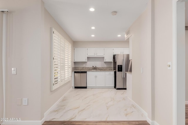 kitchen with stainless steel appliances, sink, white cabinets, and decorative backsplash