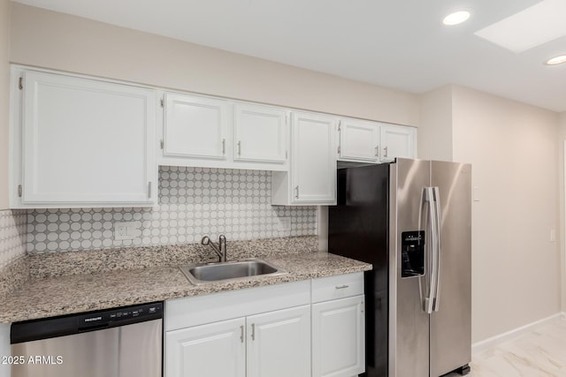 kitchen featuring appliances with stainless steel finishes, sink, white cabinets, and backsplash