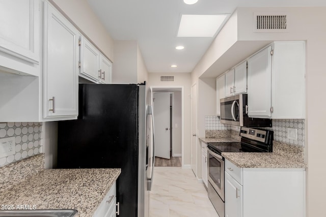 kitchen with light stone countertops, white cabinetry, appliances with stainless steel finishes, and tasteful backsplash