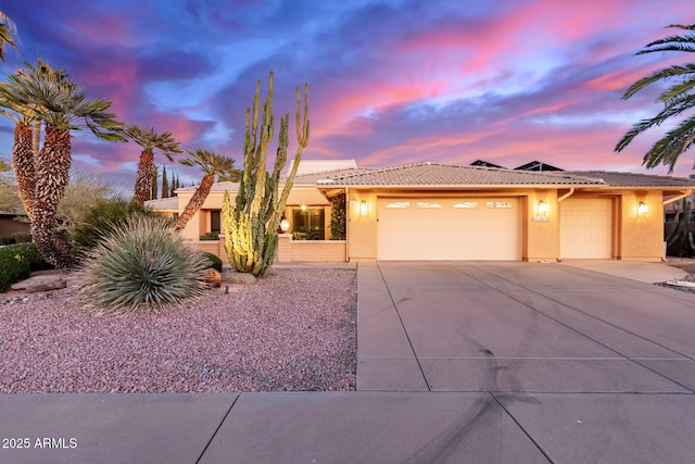 view of front facade with a garage, driveway, a tiled roof, and stucco siding