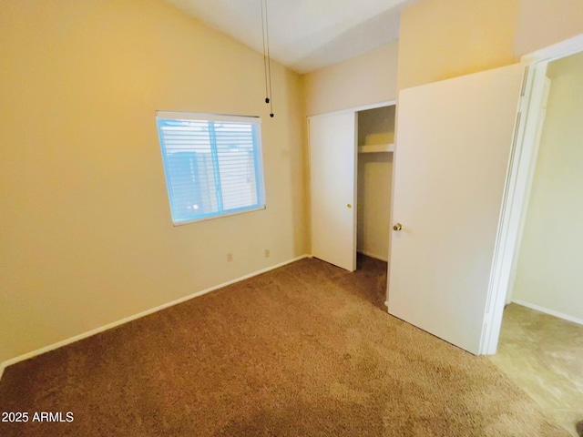 unfurnished bedroom with lofted ceiling, carpet flooring, and a closet