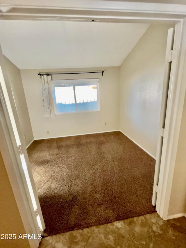 unfurnished room featuring lofted ceiling and carpet