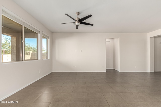 spare room with dark tile patterned floors, ceiling fan, and plenty of natural light