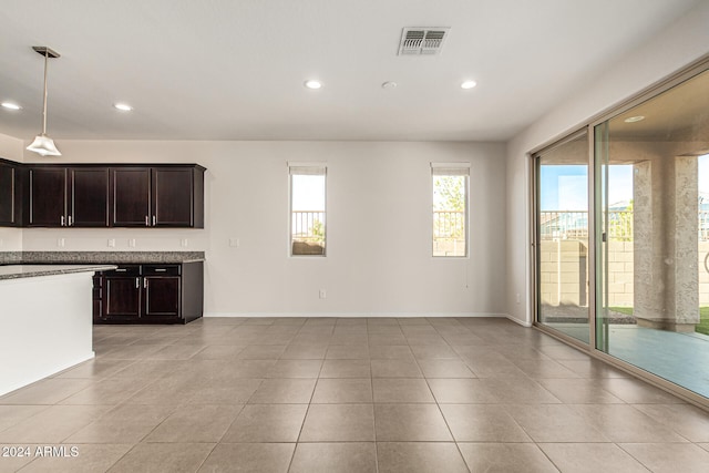 kitchen with dark brown cabinetry, light tile patterned flooring, and hanging light fixtures