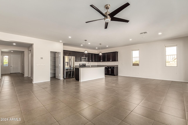 unfurnished living room featuring dark tile patterned flooring, a healthy amount of sunlight, sink, and ceiling fan