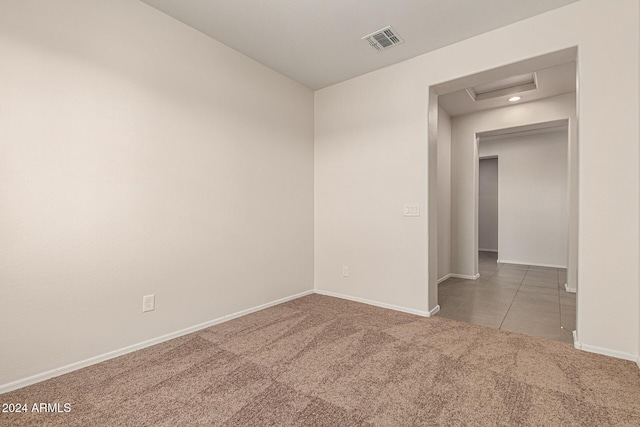 carpeted spare room featuring tile patterned flooring, baseboards, visible vents, and attic access
